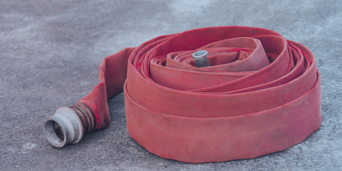 mangueira de incêndio na cor vermelha enrolada no chão