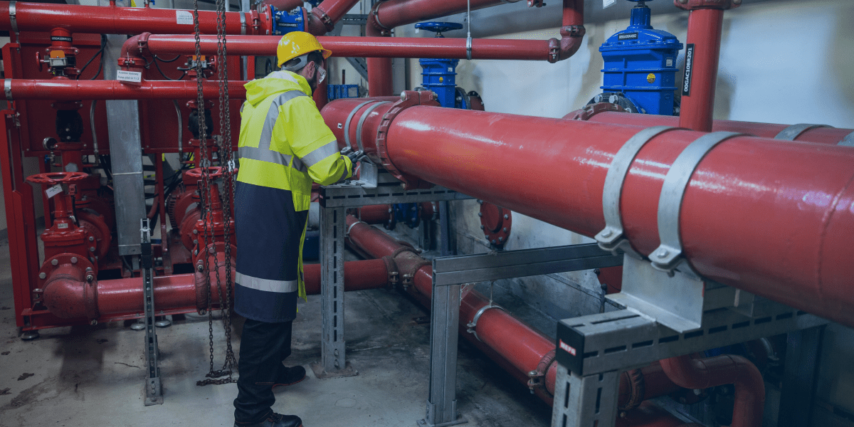 homem vestindo EPI para fazer a manutenção de tubos hidráulicos para incendio