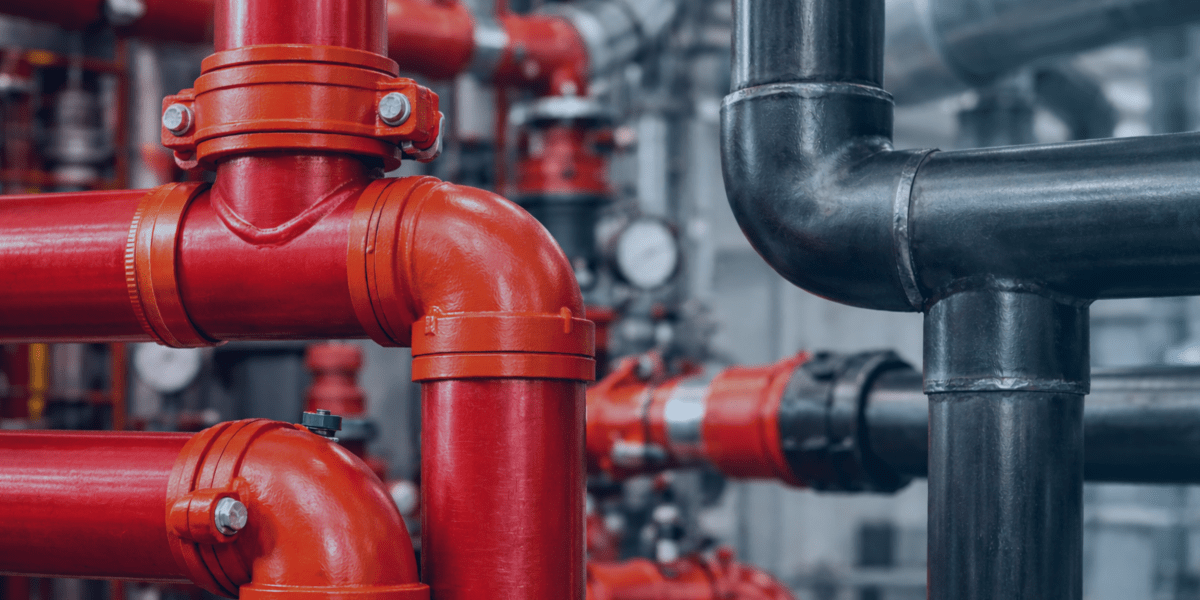 tubulação com conexões ranhuradas na cor vermelha e tubo de aço carbono lado a lado