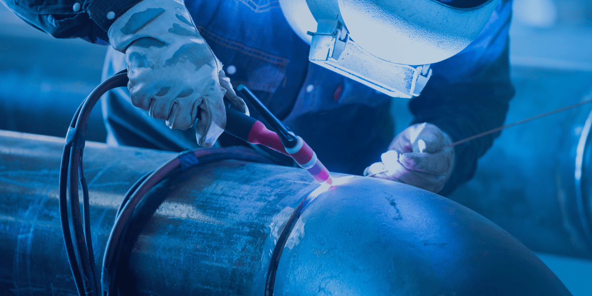 homem soldando um cotovelo ao tubo de aço carbono