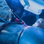 homem soldando um cotovelo ao tubo de aço carbono